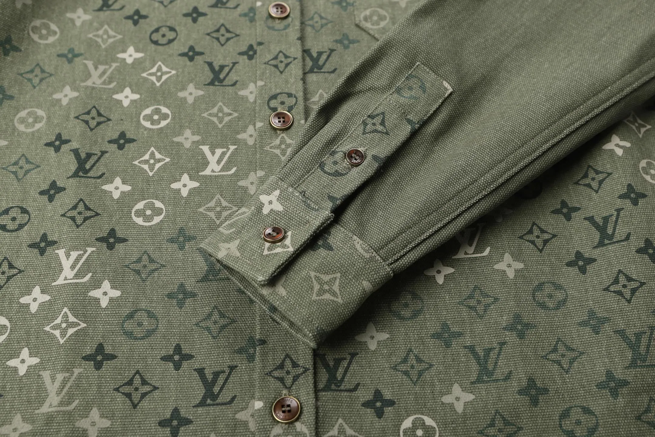 🅿️600 1v 25SS full-print green camouflage work jacket style shirt. The original purchase was 16,000 and developed. The fabric is made of custom-dyed 50-count plain double-ply pique cotton. Before positioning and cutting the fabric pieces, digital typesetting is used to lock the position of the full-print Monogram pattern to ensure that the pattern is continuous and without misalignment after splicing. The pattern alignment error between the body and the solid color splicing area is controlled within 0.5cm. The printing process uses digital direct injection technology: the pigment penetrates the fabric fibers with micron-sized particles, presenting a low-saturation vintage tone while maintaining the breathability of the fabric. The wear resistance of the printing layer reaches level 5 (friction test ≥ 200 times without falling off). The body is made of twill canvas blended fabric, and the splicing parts are reinforced with double-needle buried clip technology. The buttons are made of brass-plated matte paint, and the stitching is made of high-tenacity nylon thread with a tensile strength of 150N. The overall process takes into account both visual integrity and practical durability. The overall wiring is straight and delicate, the fabric is comfortable and soft, and the color is consistent without color difference. It can be matched with the same style to create a fashionable look and control various occasions. Customized accessories, complete with three standards, the same style for men and women. Size:S-M-L-XL